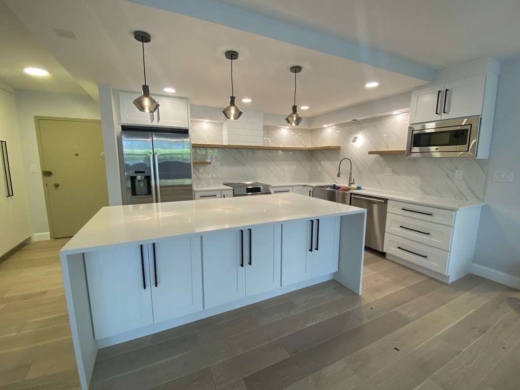 a kitchen with kitchen island a sink stainless steel appliances and cabinets