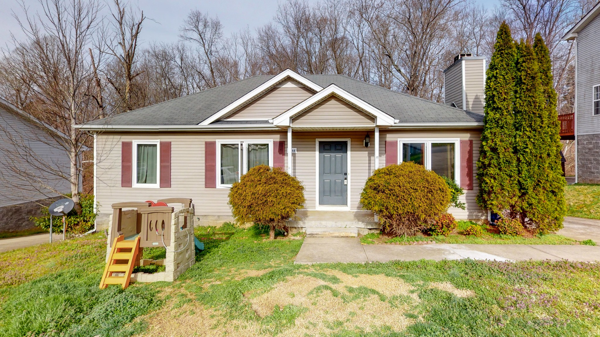 a front view of house with yard and trees in the background