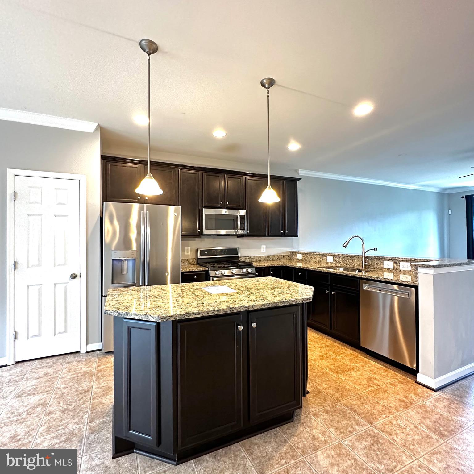 a kitchen with stainless steel appliances granite countertop a sink a stove and a wooden floor