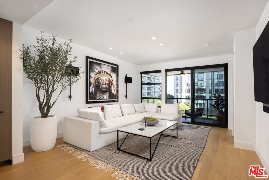 a living room with furniture large window and wooden floor