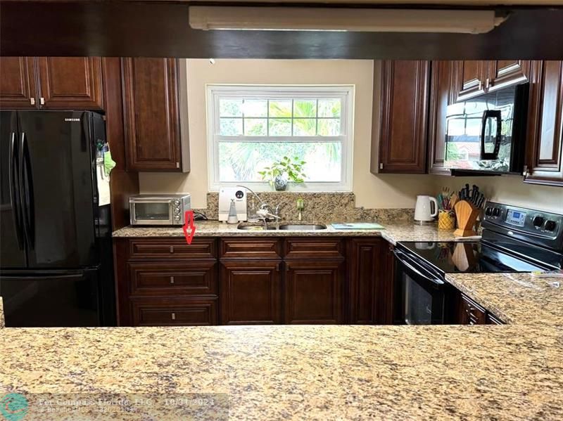 a kitchen with granite countertop a refrigerator stove top oven and sink