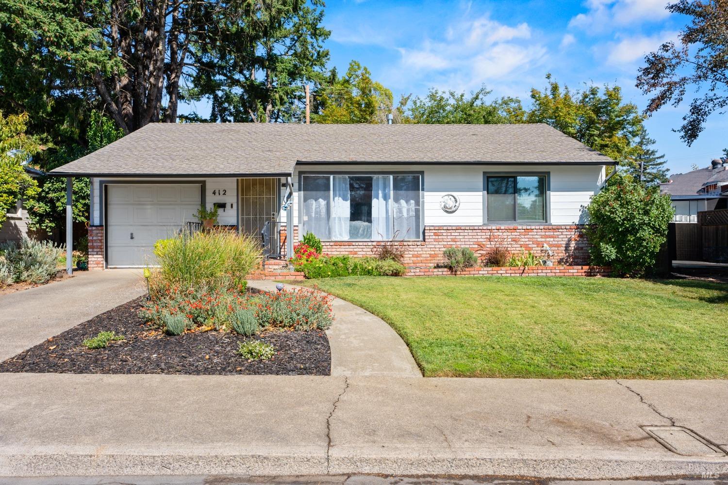 a front view of a house with a yard and potted plants