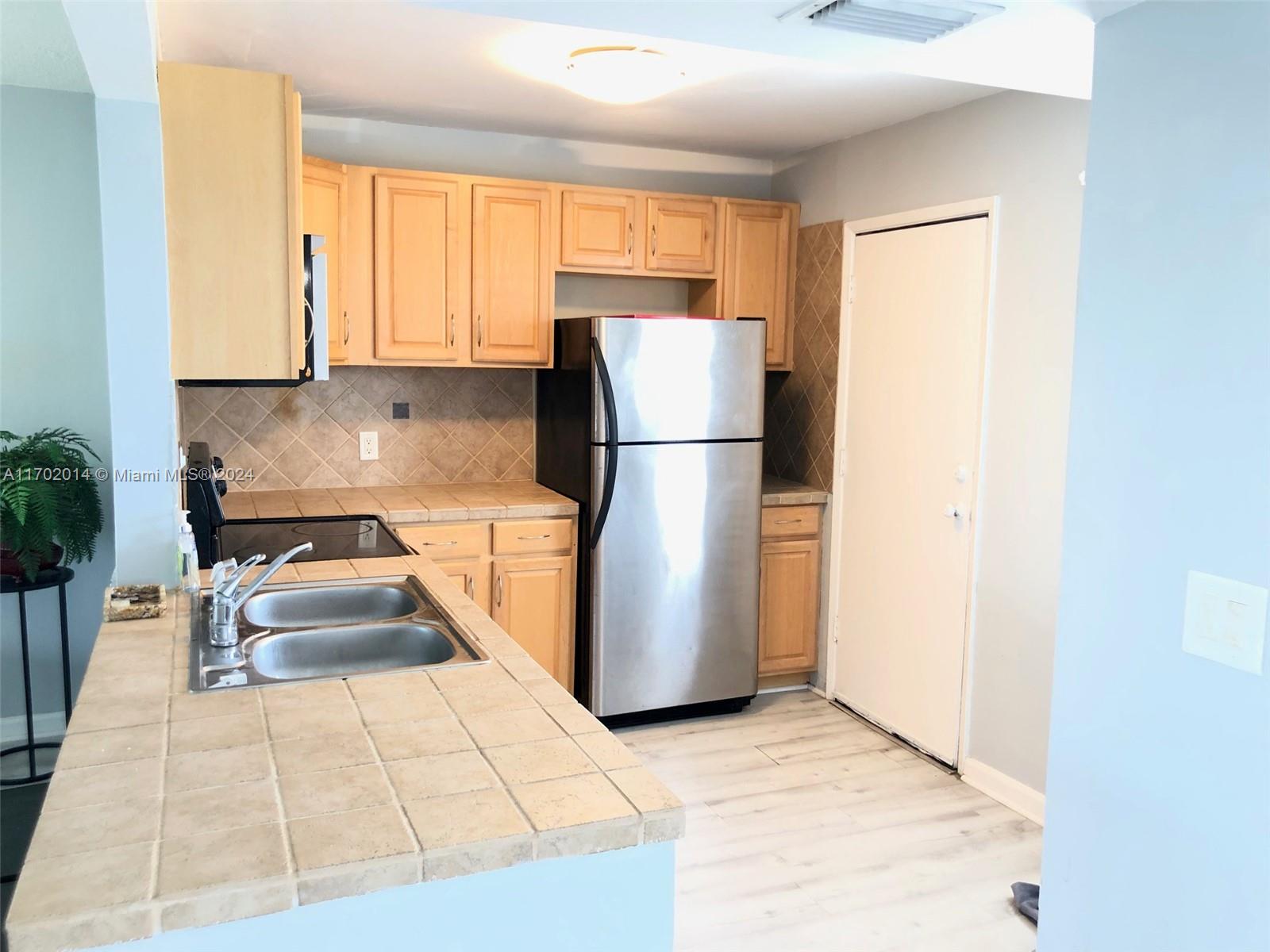 a kitchen with a refrigerator a stove top oven and a window