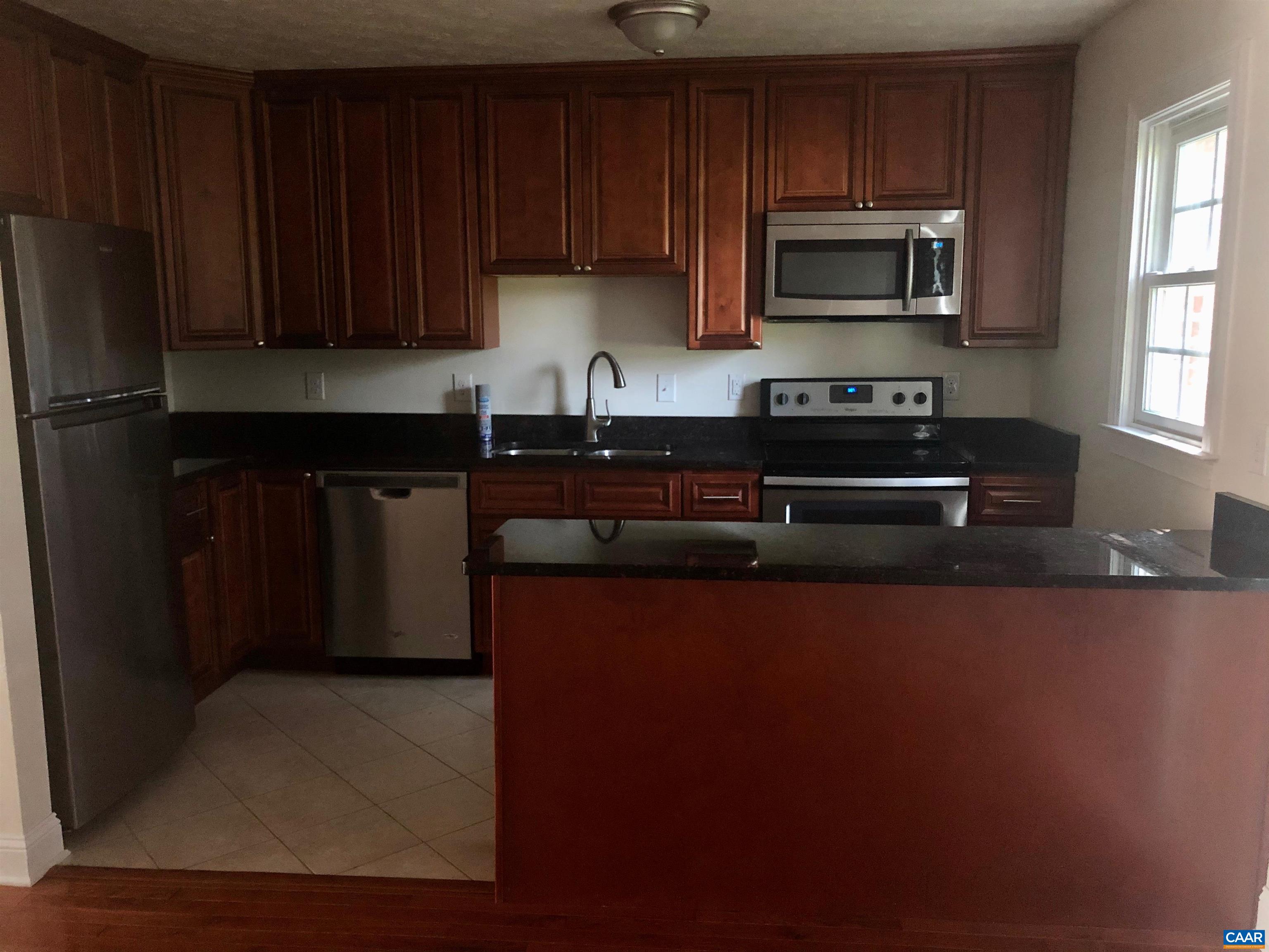 a kitchen with granite countertop wooden cabinets a refrigerator and a sink