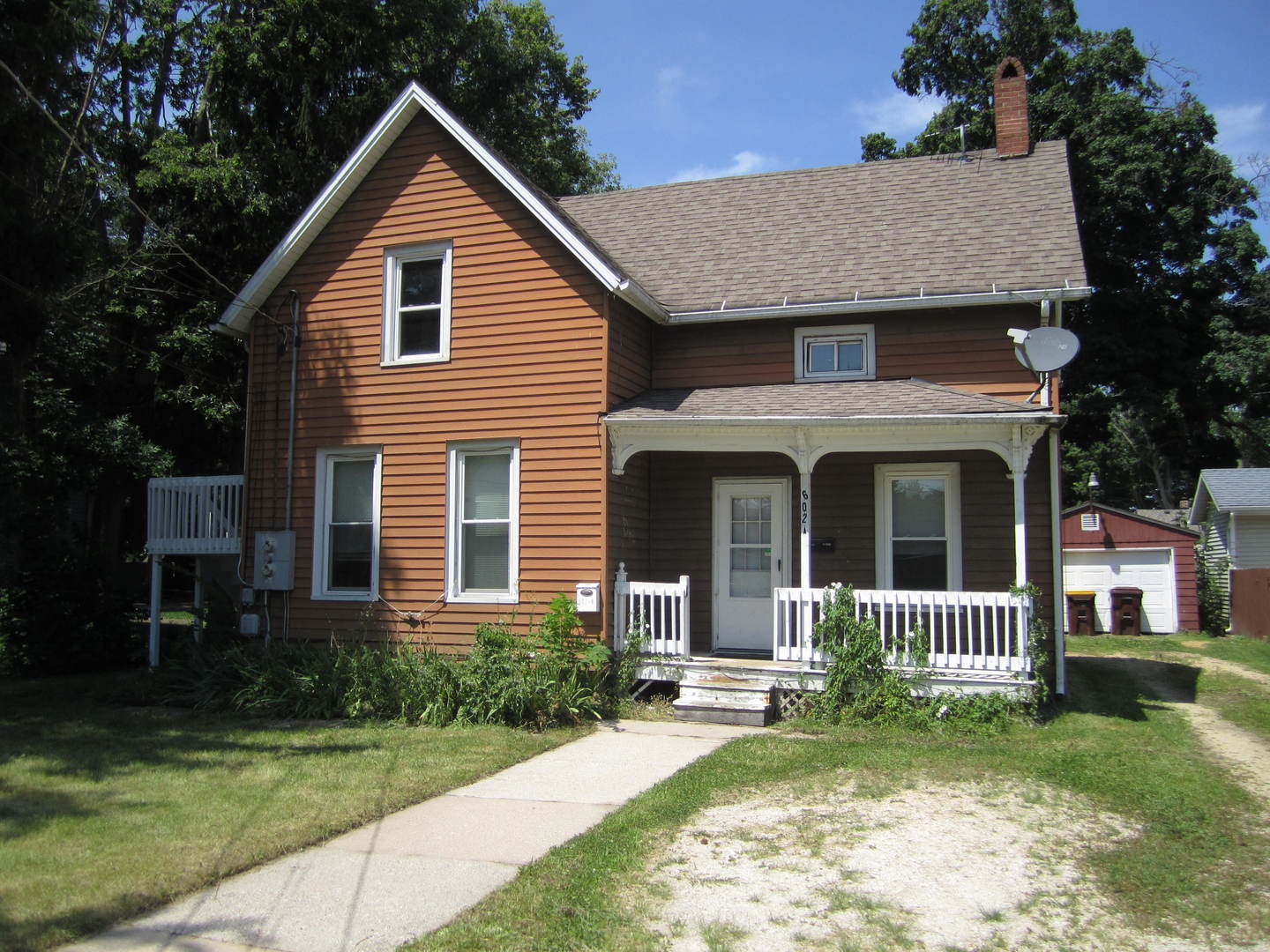 a view of a house with a yard plants and a large tree