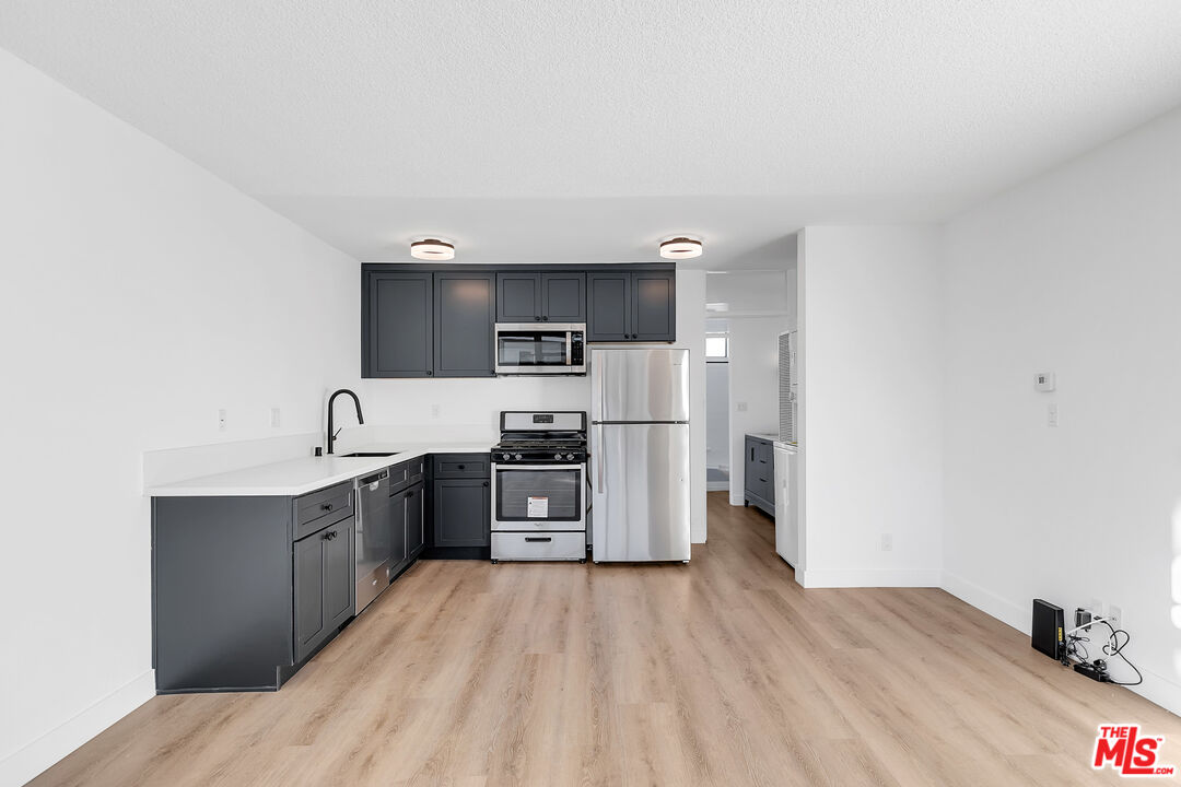 a kitchen with stainless steel appliances a sink cabinets and wooden floor