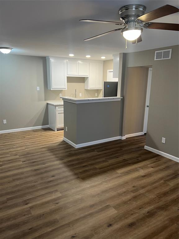 a view of kitchen and empty room with wooden floor