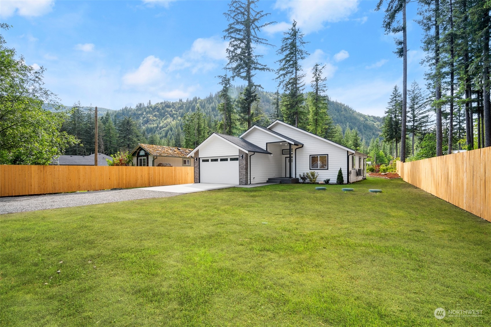 a white house with a small yard and large trees