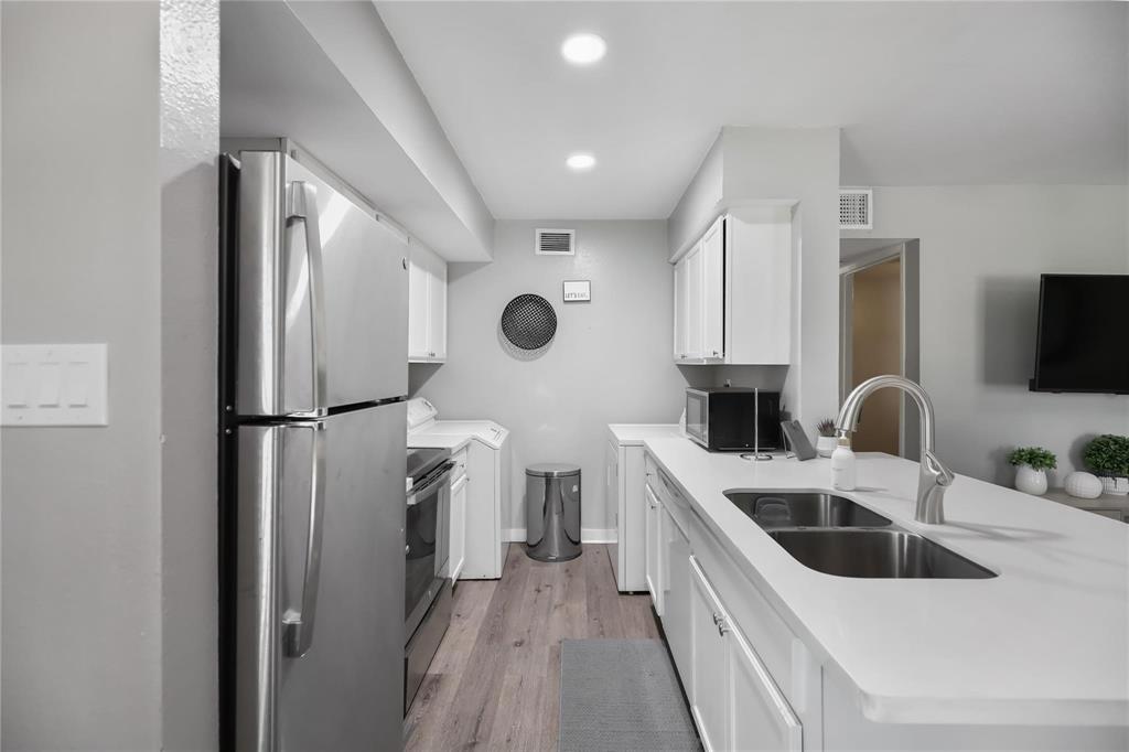 a kitchen with a sink a refrigerator a microwave and cabinets