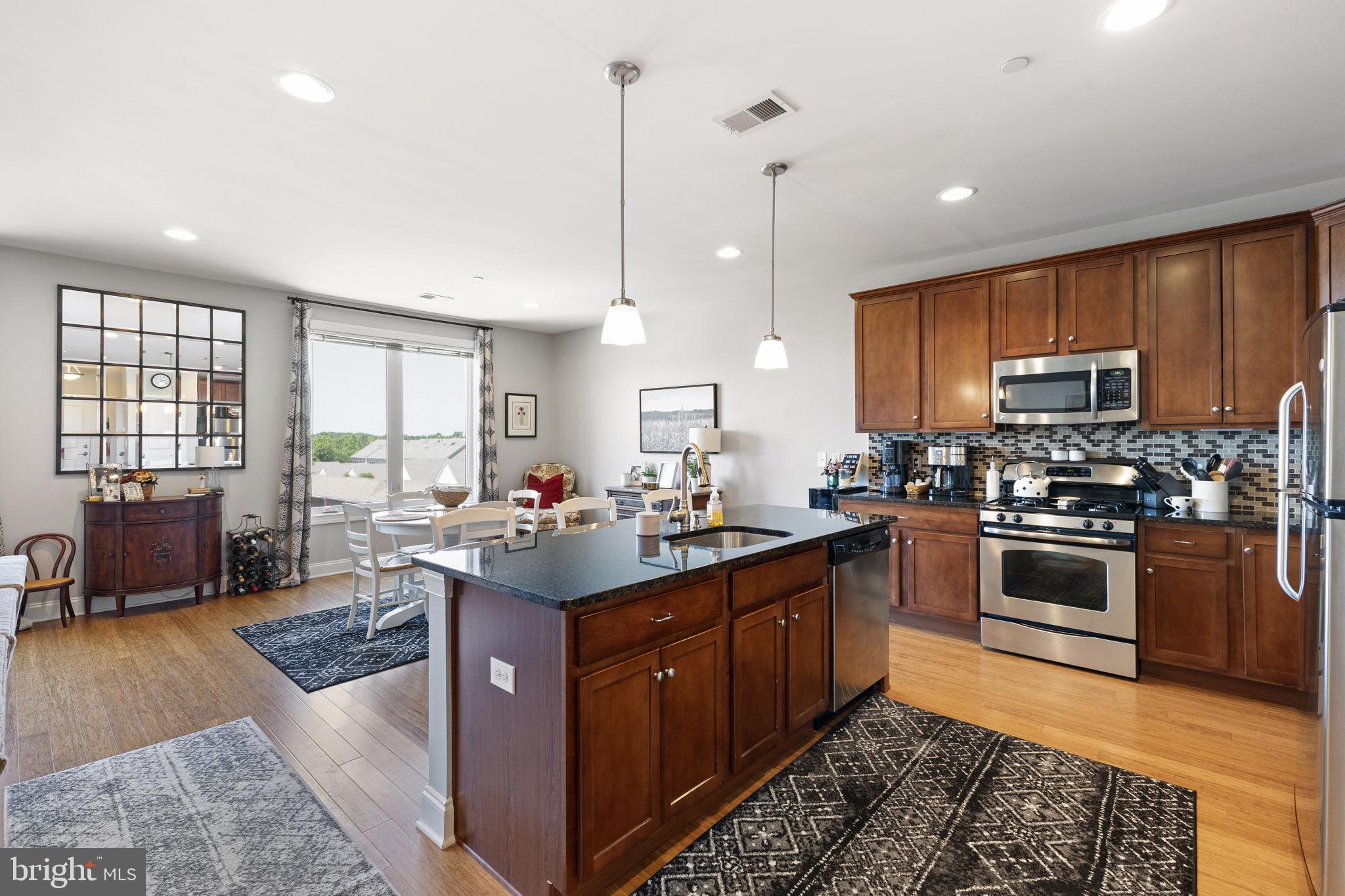a kitchen with stainless steel appliances kitchen island granite countertop a sink counter space cabinets and a window