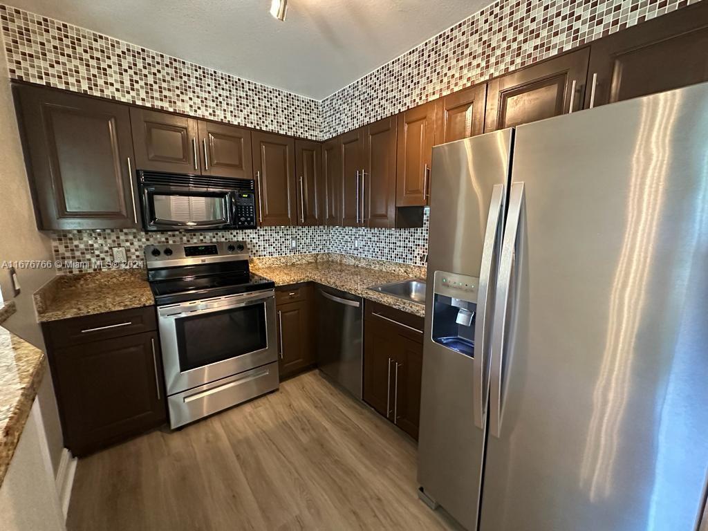 a kitchen with granite countertop a refrigerator stove and microwave