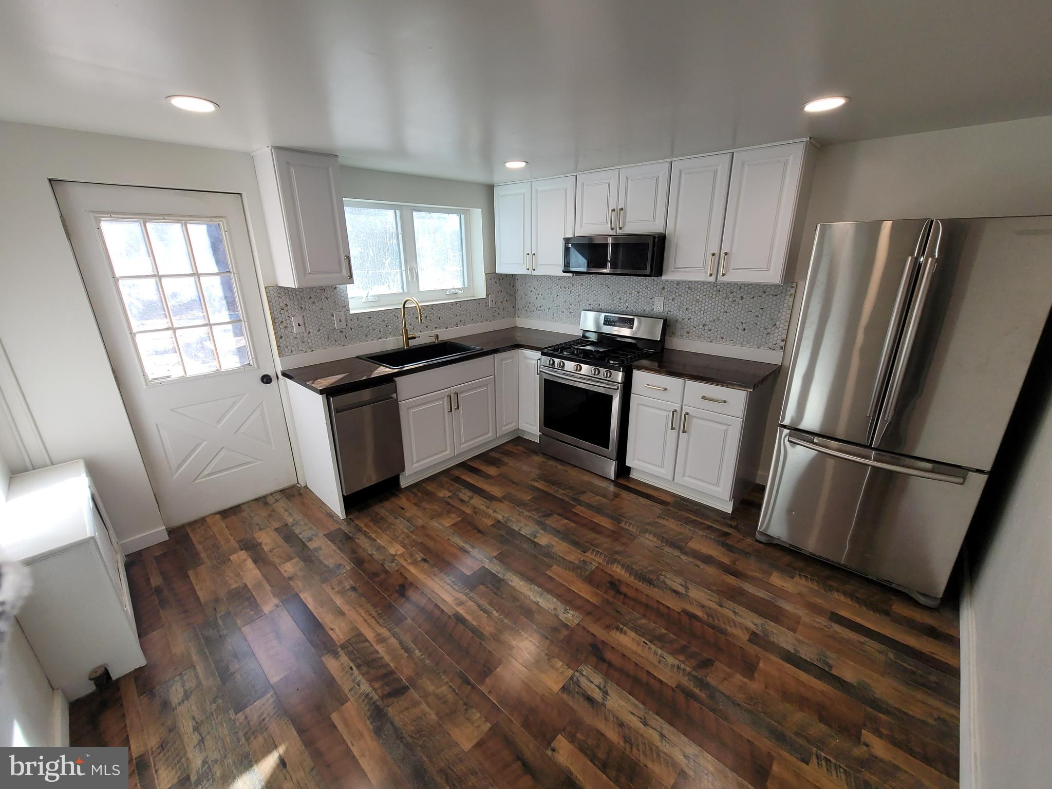 a kitchen with granite countertop a refrigerator stove and sink