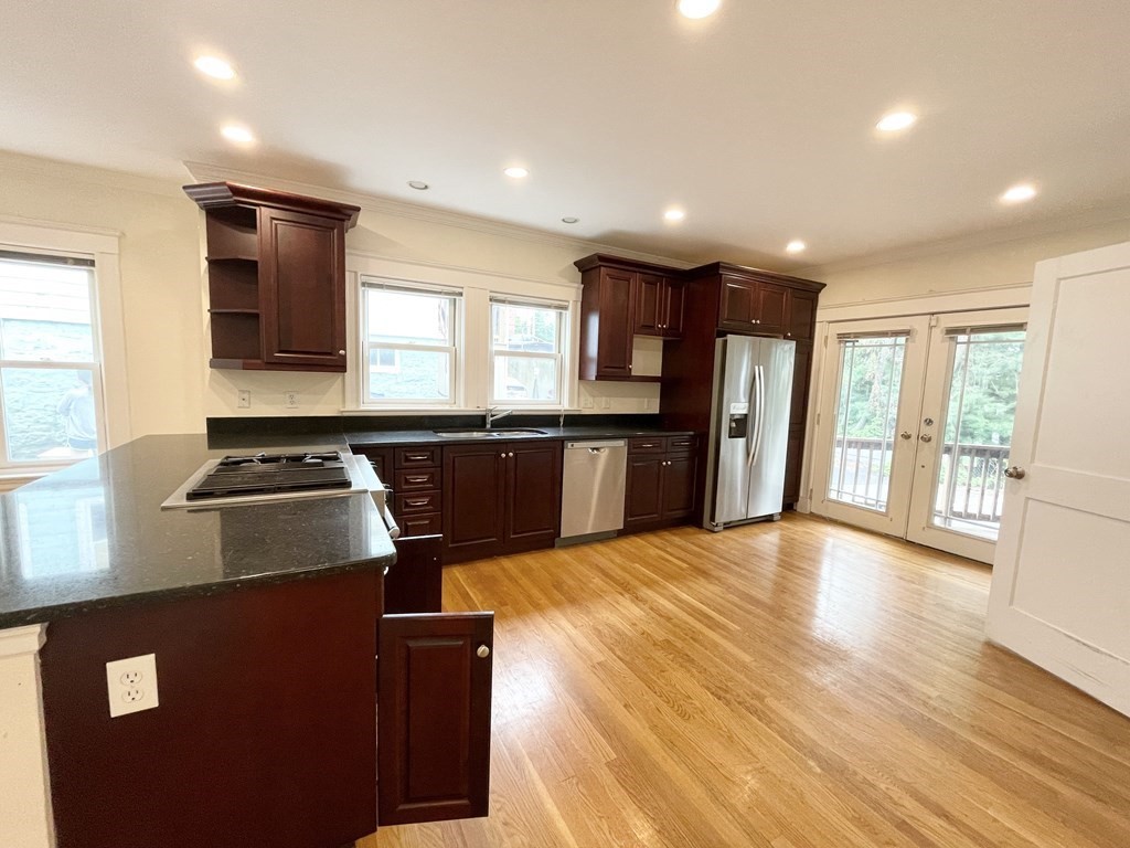 a kitchen with stainless steel appliances granite countertop a refrigerator a sink dishwasher a stove and a refrigerator with wooden floor