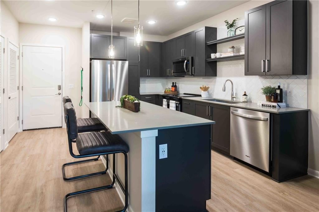 a kitchen with kitchen island a counter top space a sink stainless steel appliances and cabinets