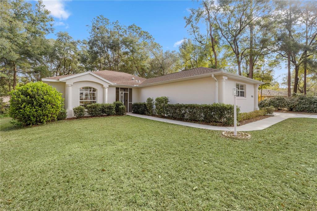 a view of a house with a yard and large trees