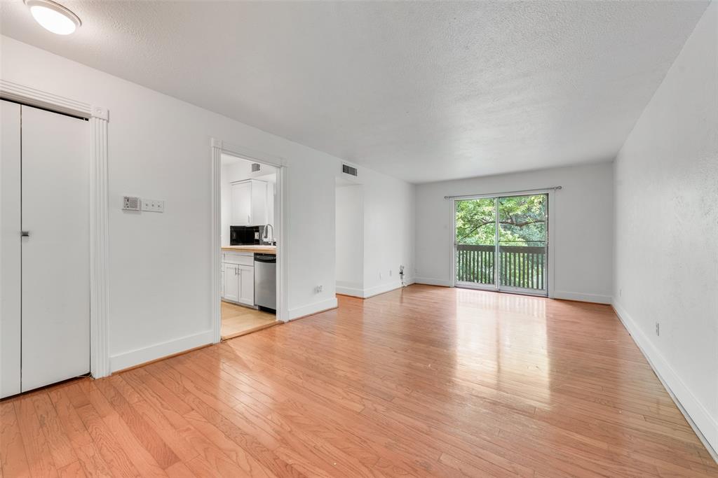 a view of empty room with wooden floor and window