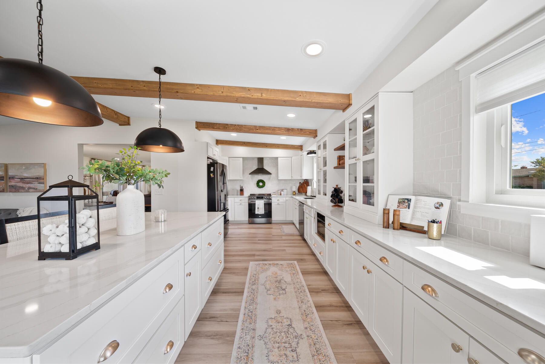 a large white kitchen with stainless steel appliances kitchen island granite countertop a lot of counter space and a large window