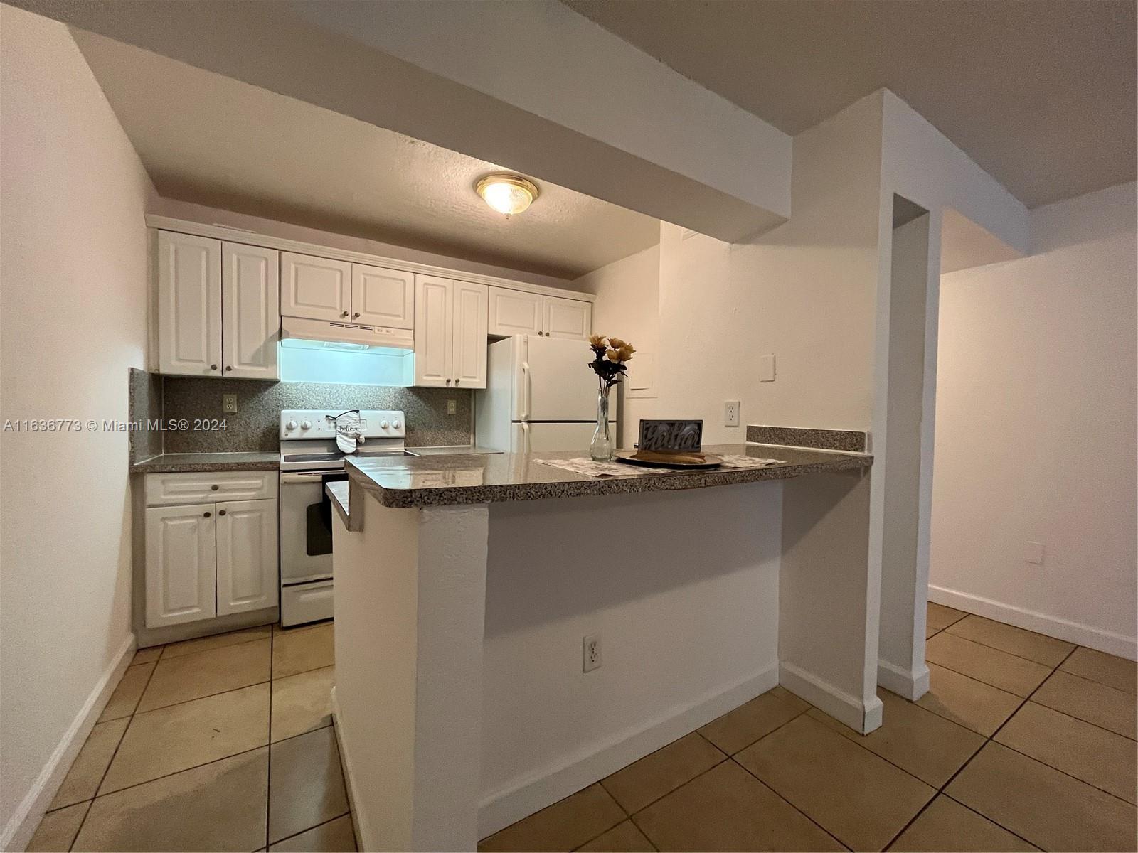 a kitchen with kitchen island granite countertop a sink cabinets and stainless steel appliances