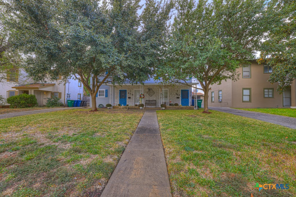 a front view of a house with a yard and trees