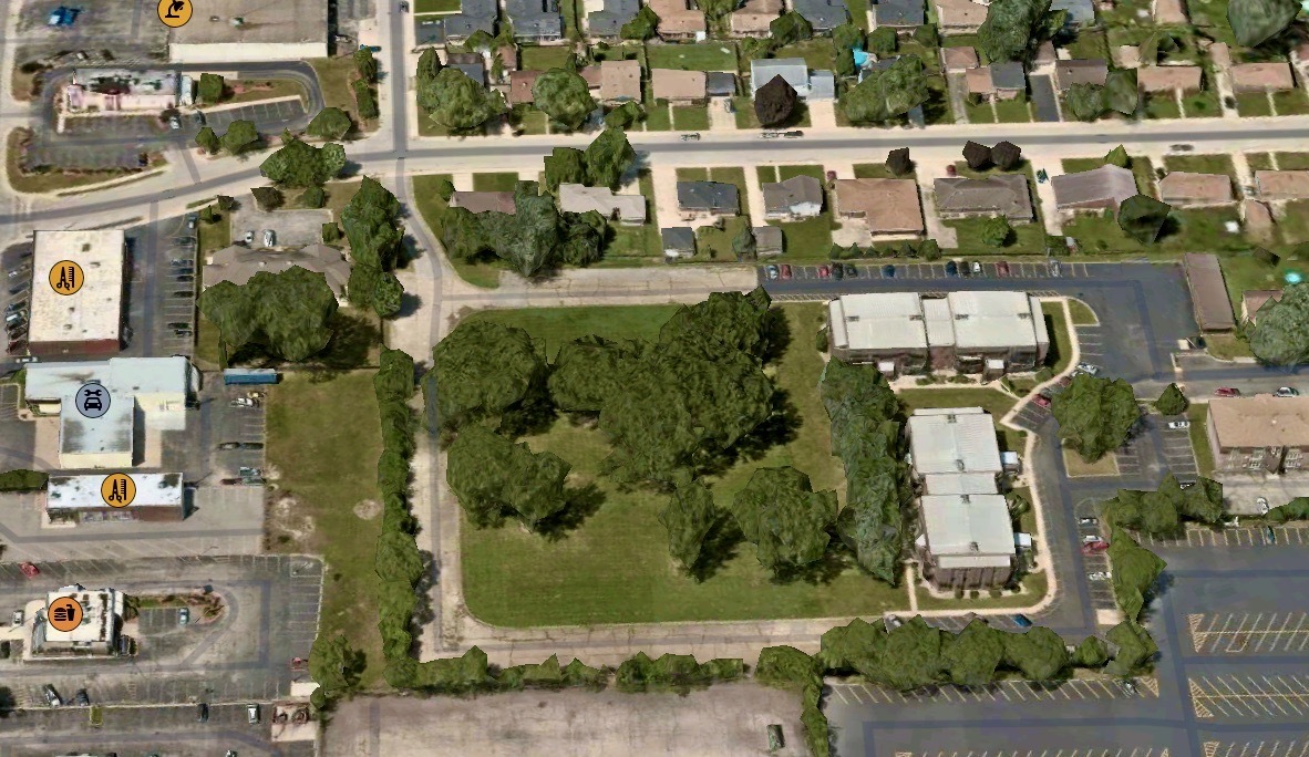 an aerial view of a residential apartment building with a yard and parking spaces