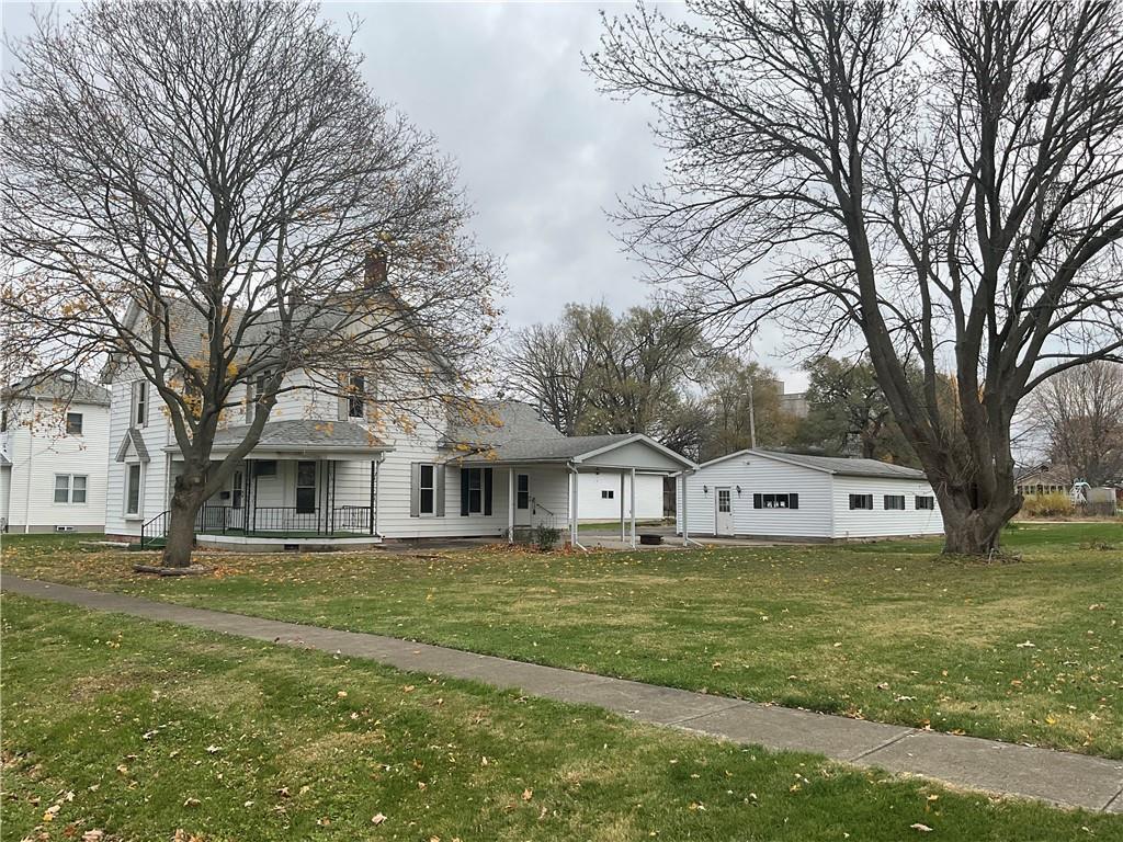 a view of house with a big yard and large trees