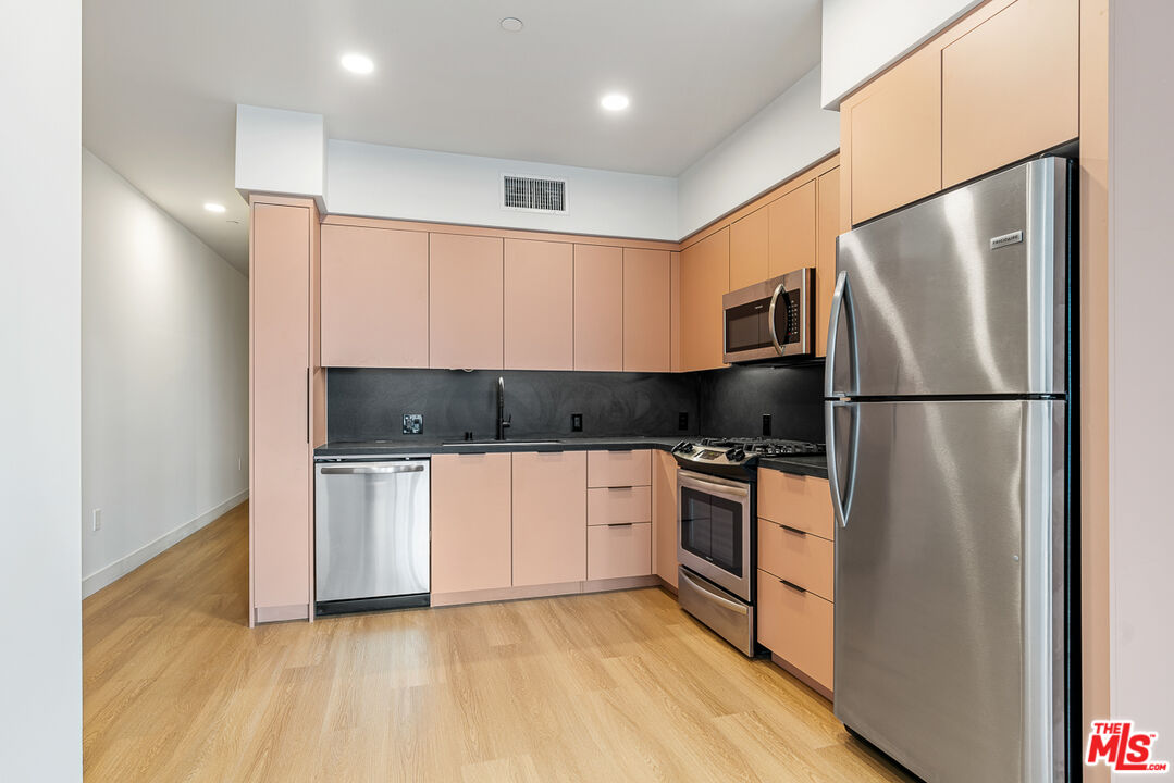 a kitchen with stainless steel appliances granite countertop a refrigerator and a stove top oven