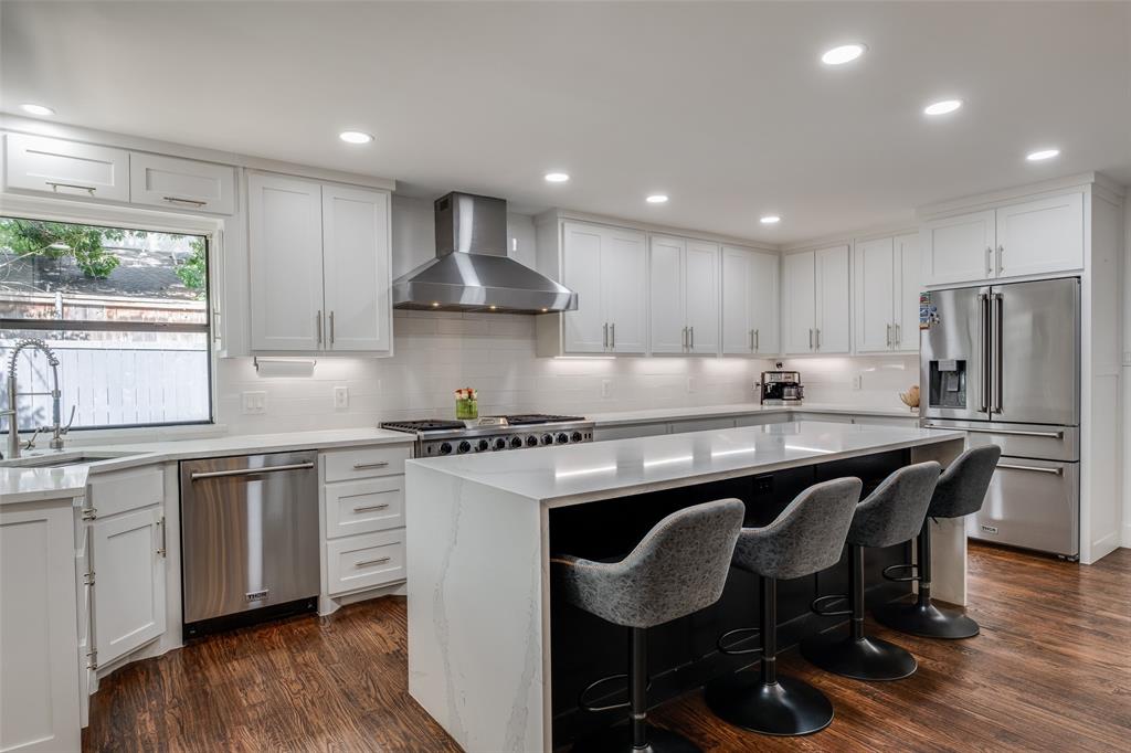 a kitchen with stainless steel appliances granite countertop a table chairs sink refrigerator and microwave