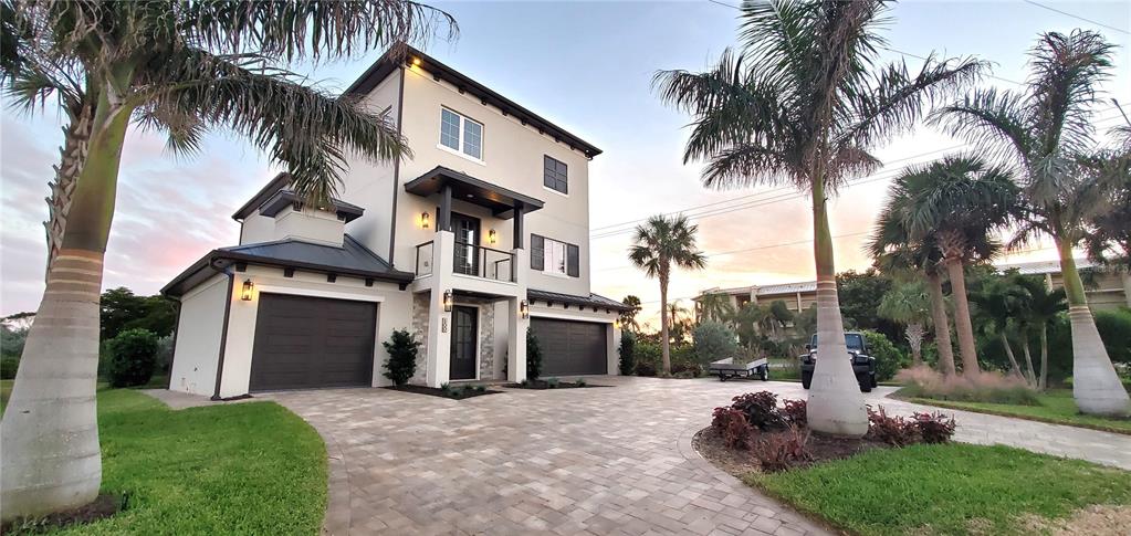 a front view of a house with a garden and palm trees