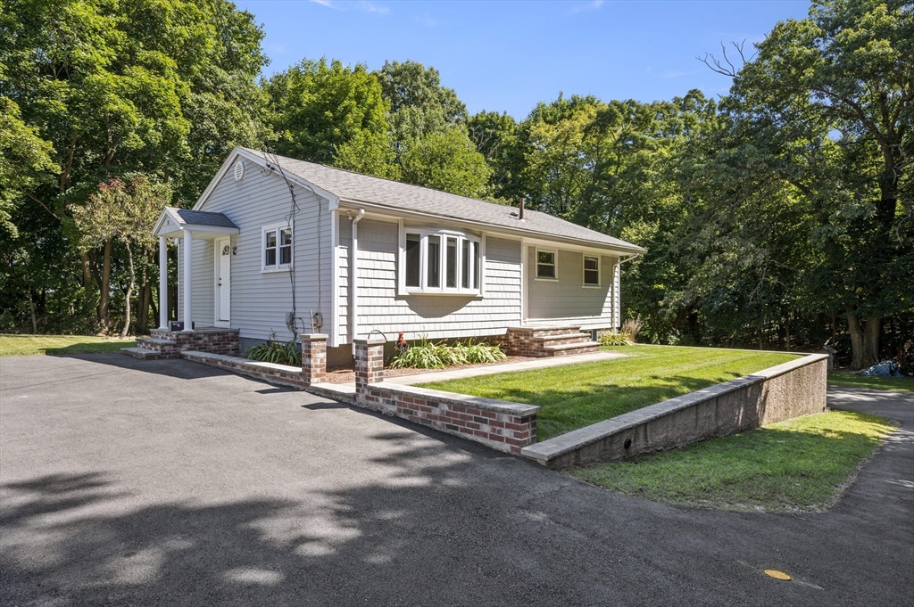 a front view of house with yard and trees in the background