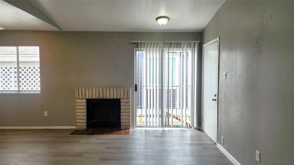 an empty room with wooden floor fireplace and windows