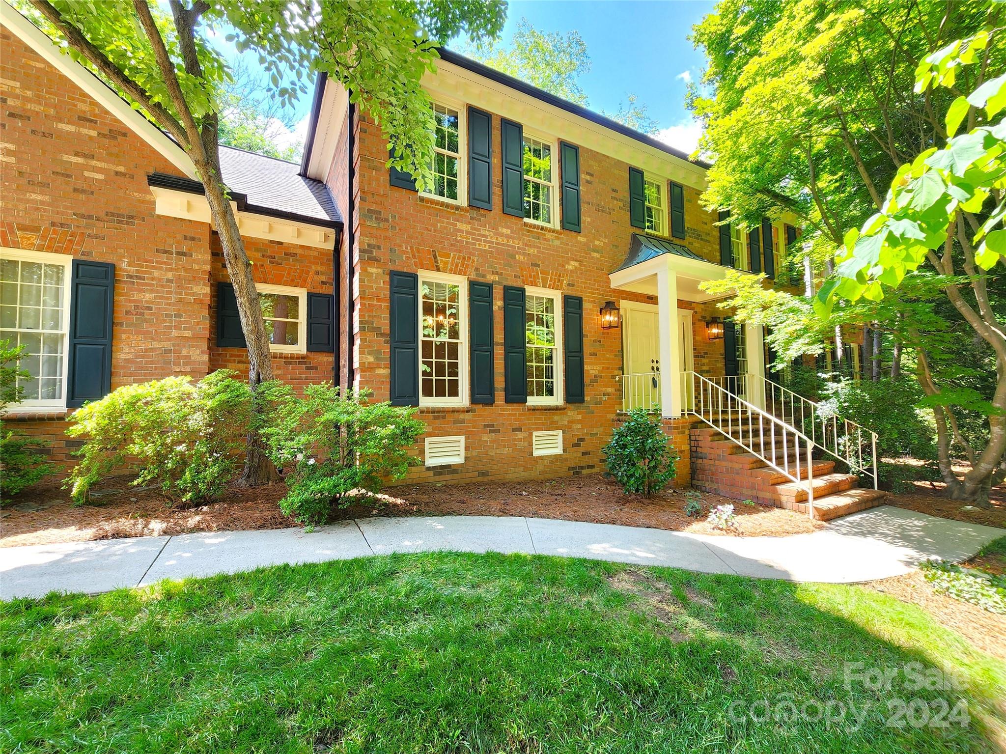 a view of a brick house with a yard and plants