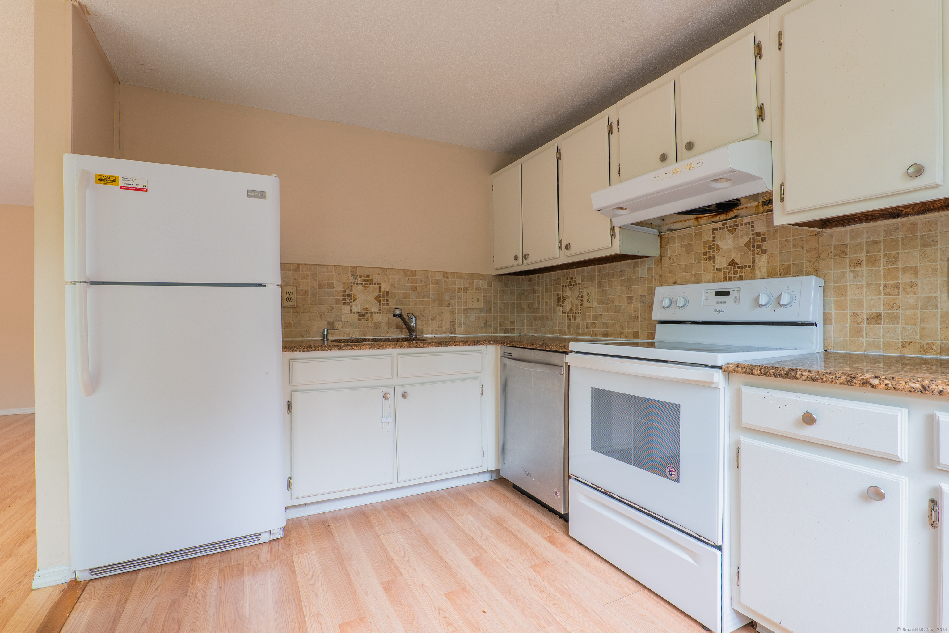 a kitchen with granite countertop white cabinets and white appliances