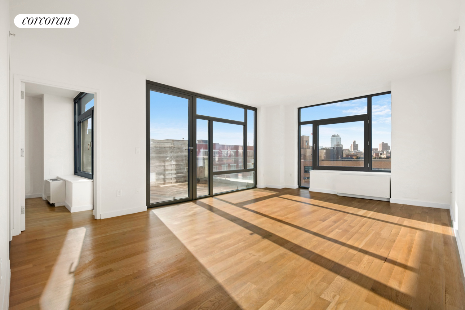 a view of an empty room with wooden floor and a window