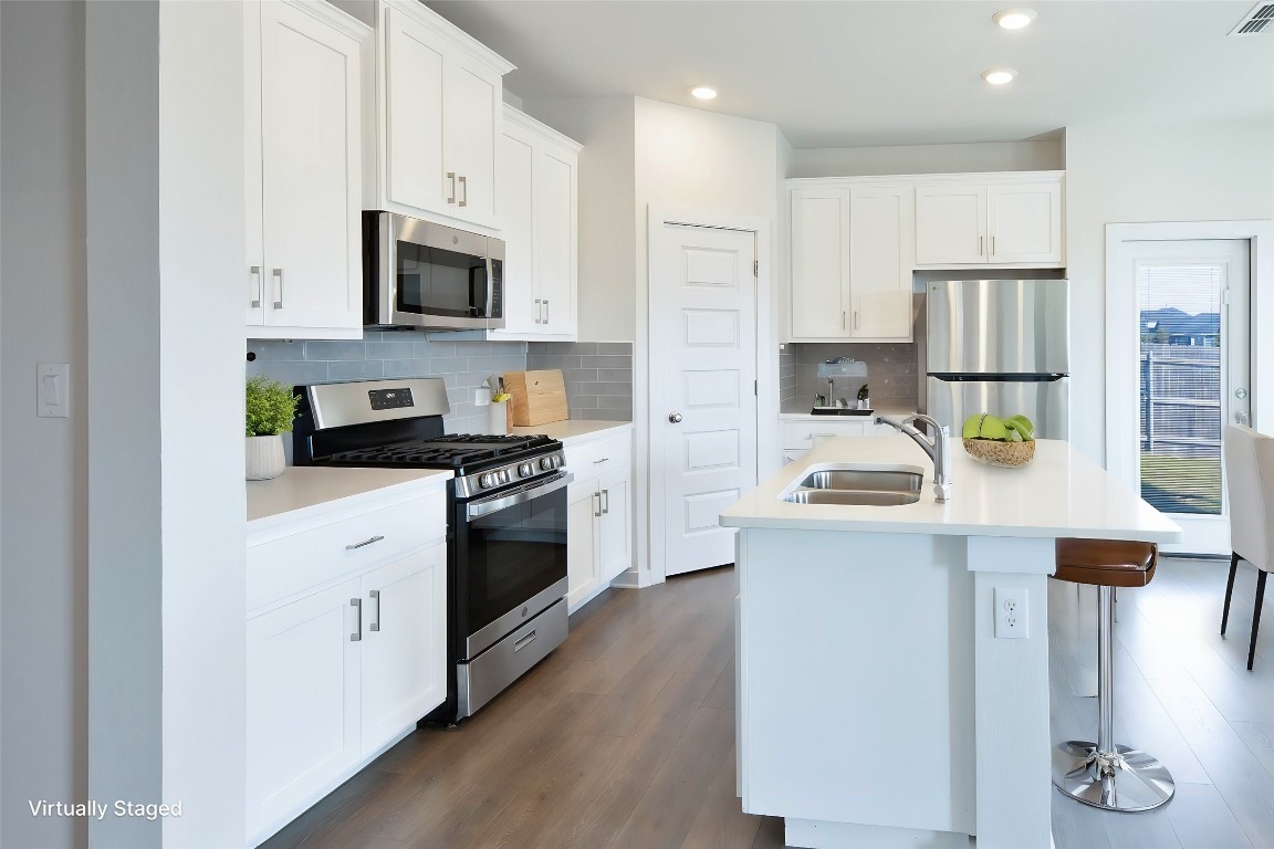 a kitchen with stainless steel appliances a stove a sink and white cabinets