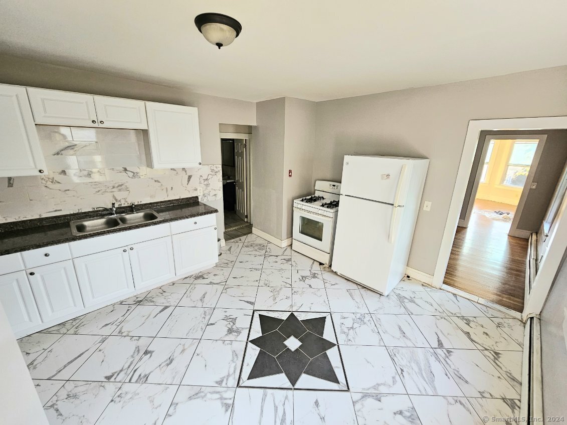 a large white kitchen with a stove a sink and a refrigerator