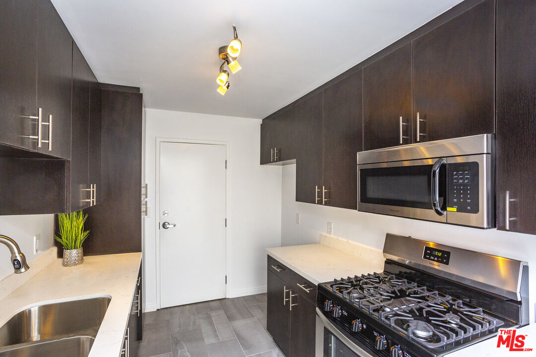 a kitchen with stainless steel appliances a stove a microwave and sink