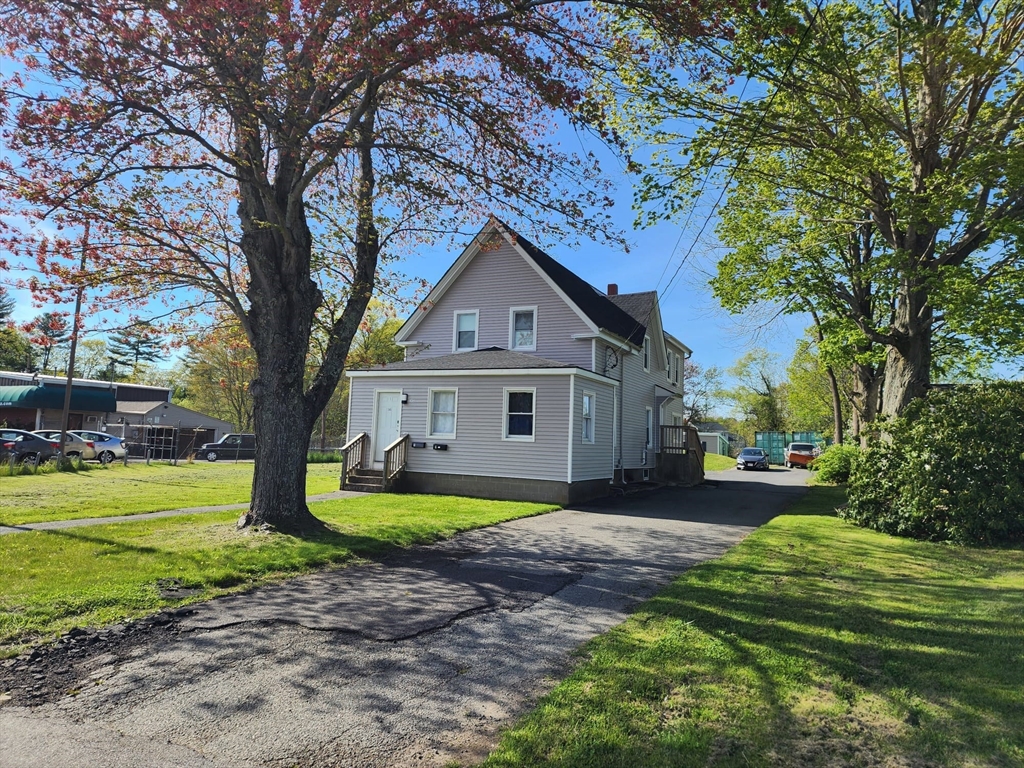 a front view of a house with garden and trees