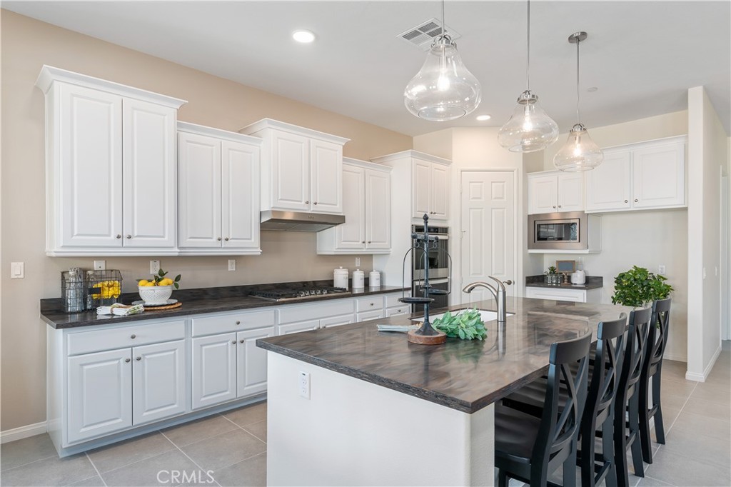 a kitchen with kitchen island granite countertop a white cabinets and chairs