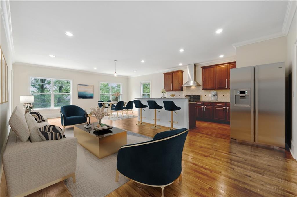 a living room with couches a kitchen counter space and stainless steel appliances