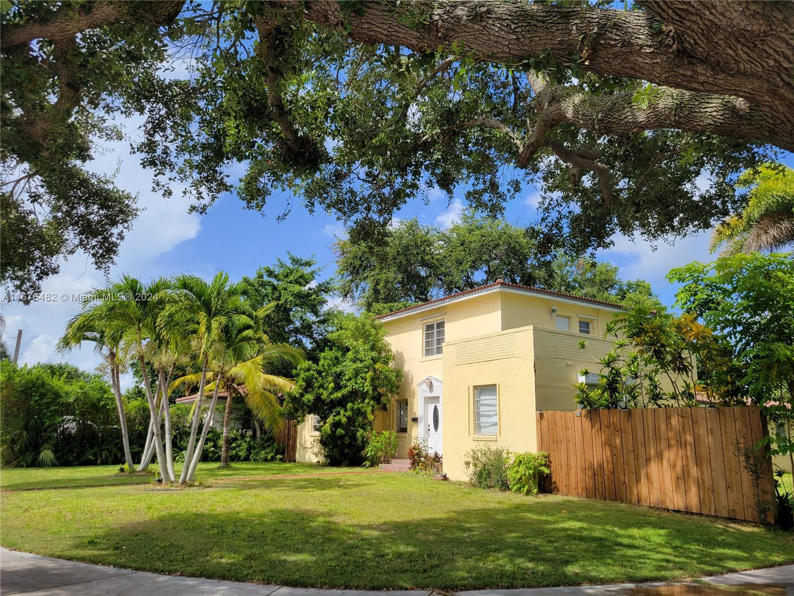 a view of a white house with a big yard and large trees