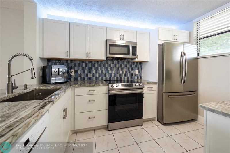 a kitchen with granite countertop white cabinets and stainless steel appliances