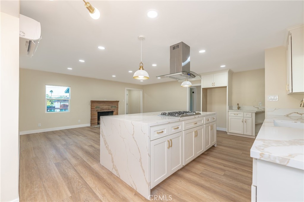 a large kitchen with kitchen island a stove a sink a refrigerator and a fireplace