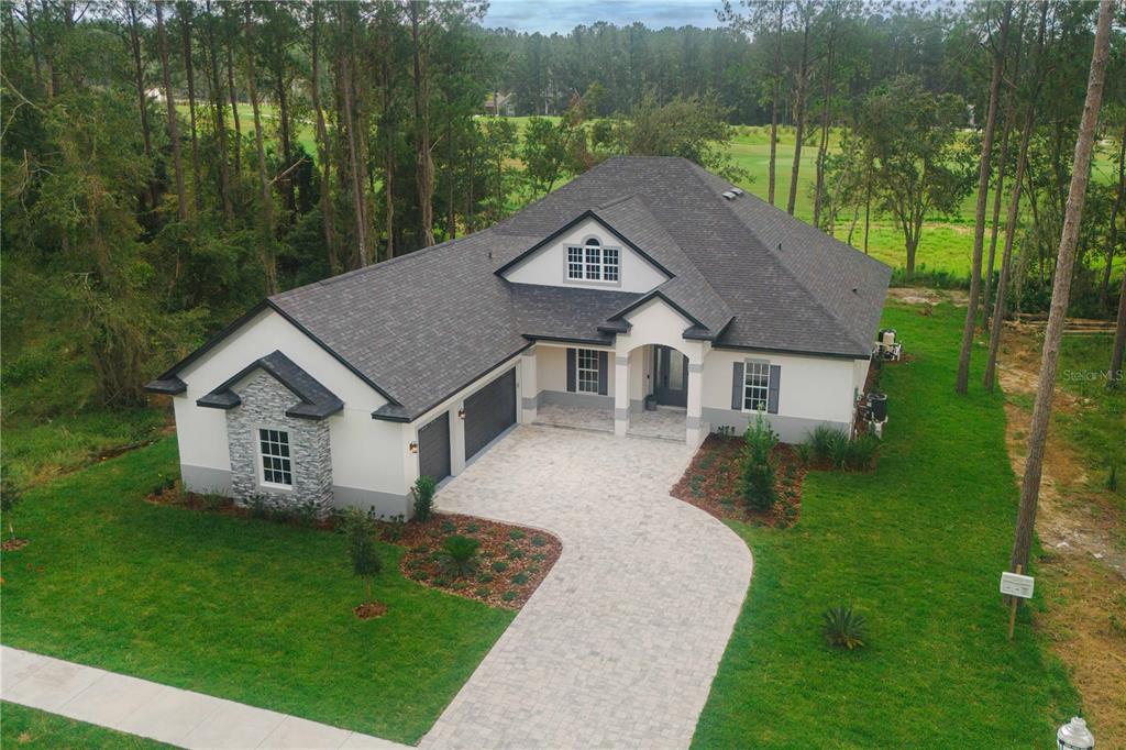 a aerial view of a house next to a big yard and large trees