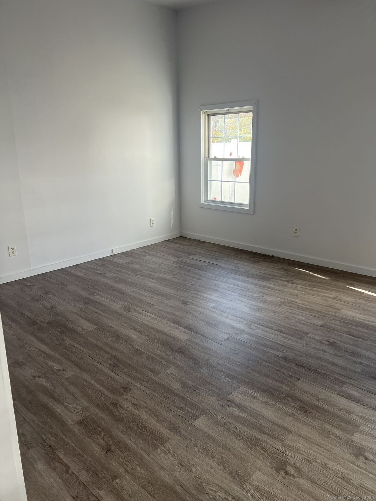 an empty room with wooden floor and window