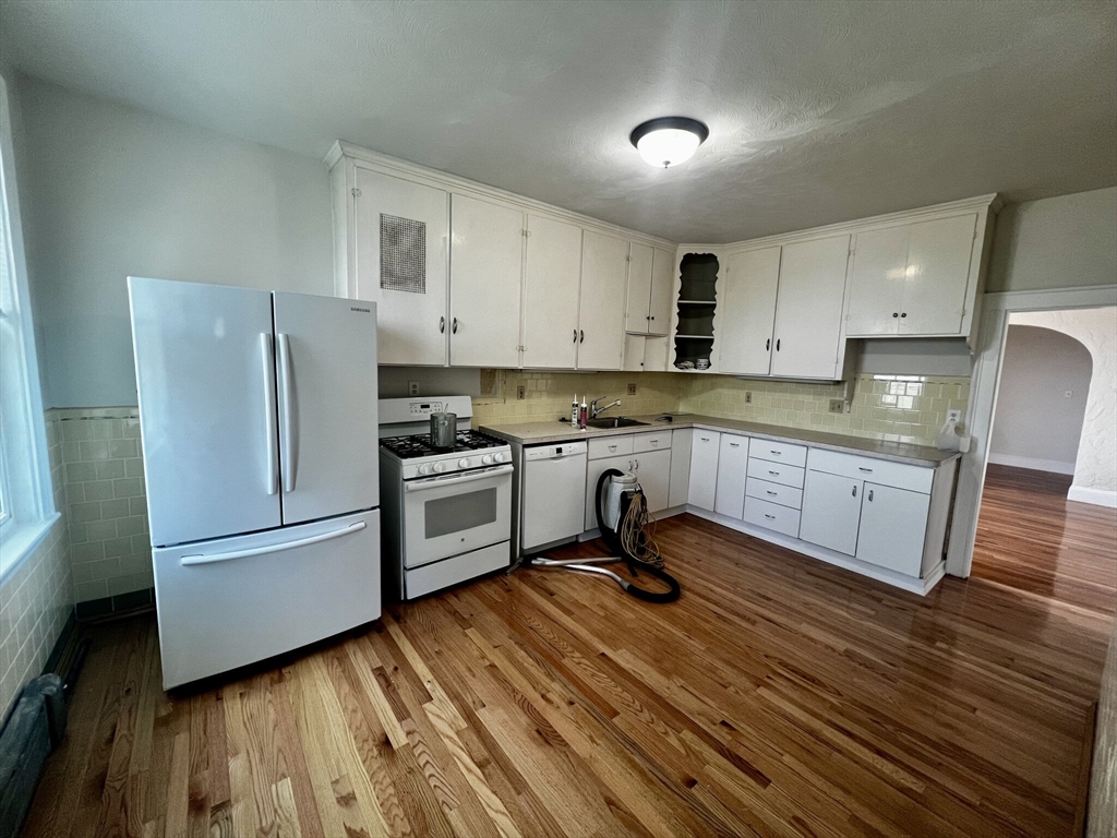 a kitchen with granite countertop stainless steel appliances a sink cabinets and wooden floor