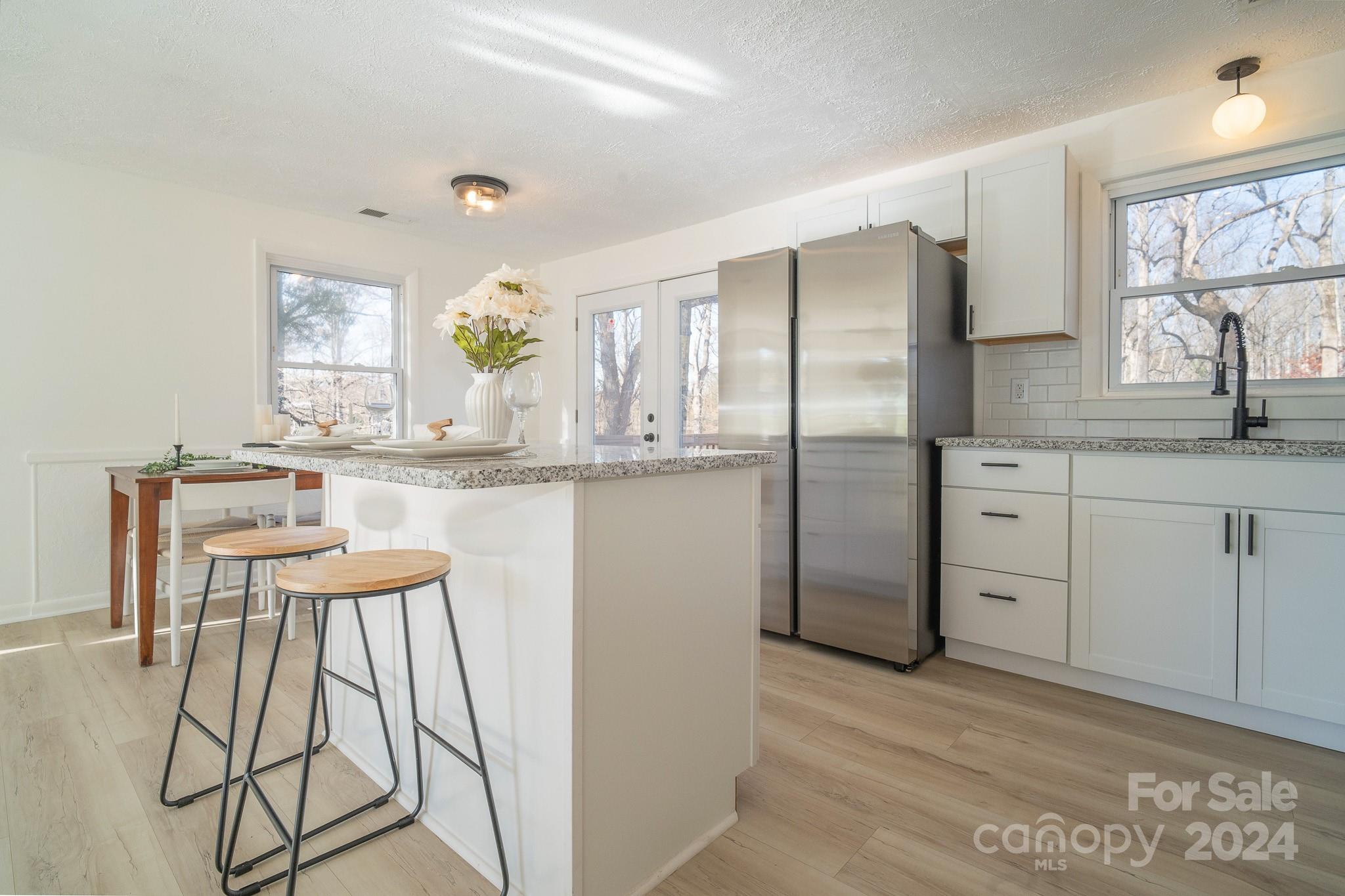 a kitchen with stainless steel appliances granite countertop a refrigerator a sink and white cabinets