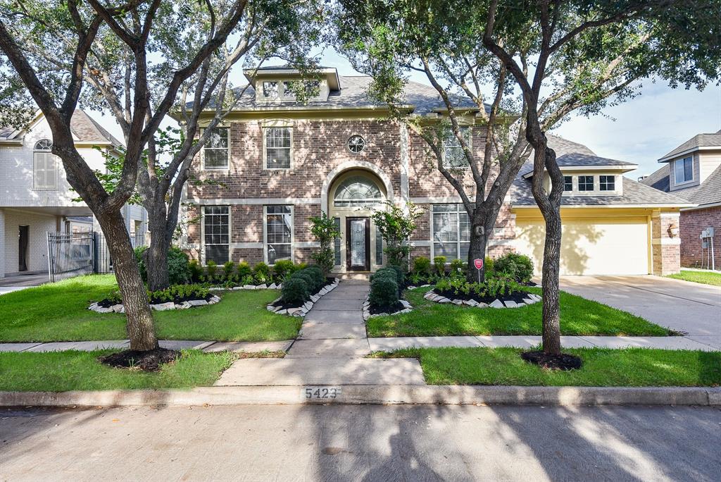 a front view of a house with a garden and trees