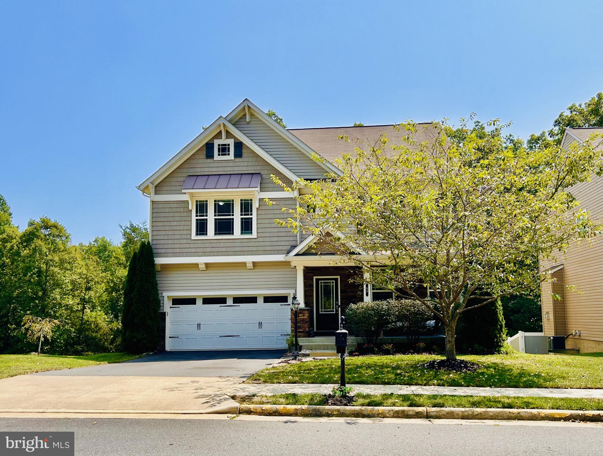 a front view of a house with a garden and tree