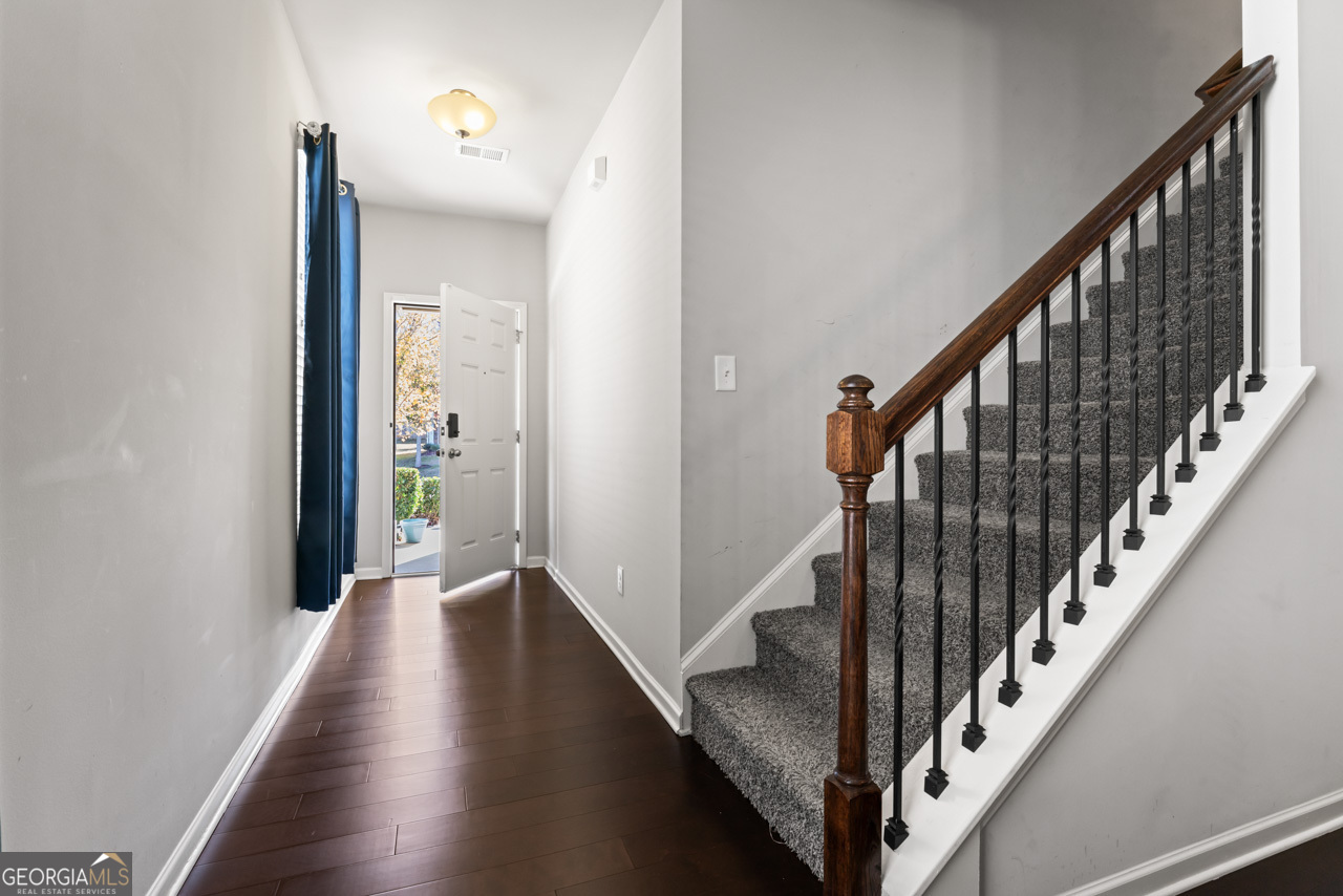 a view of a hallway with wooden floor and stairs