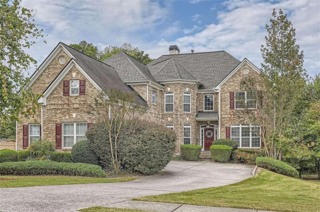 a view of a brick house next to a yard with big trees